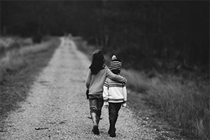 two children walking with arm over shoulder